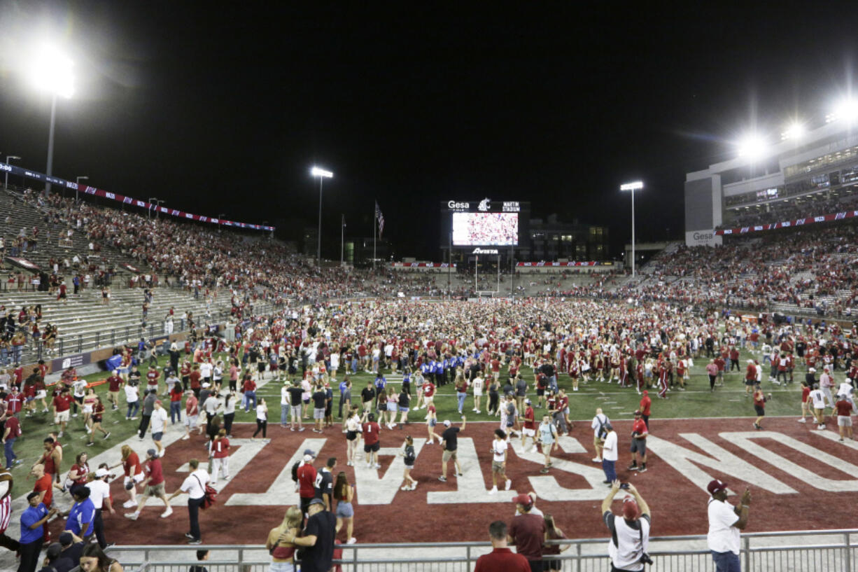 Washington State fans celebrate on the field after team's win over Wisconsin in an NCAA college football game, Saturday, Sept. 9, 2023, in Pullman, Wash.