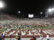 Washington State fans celebrate on the field after team's win over Wisconsin in an NCAA college football game, Saturday, Sept. 9, 2023, in Pullman, Wash.