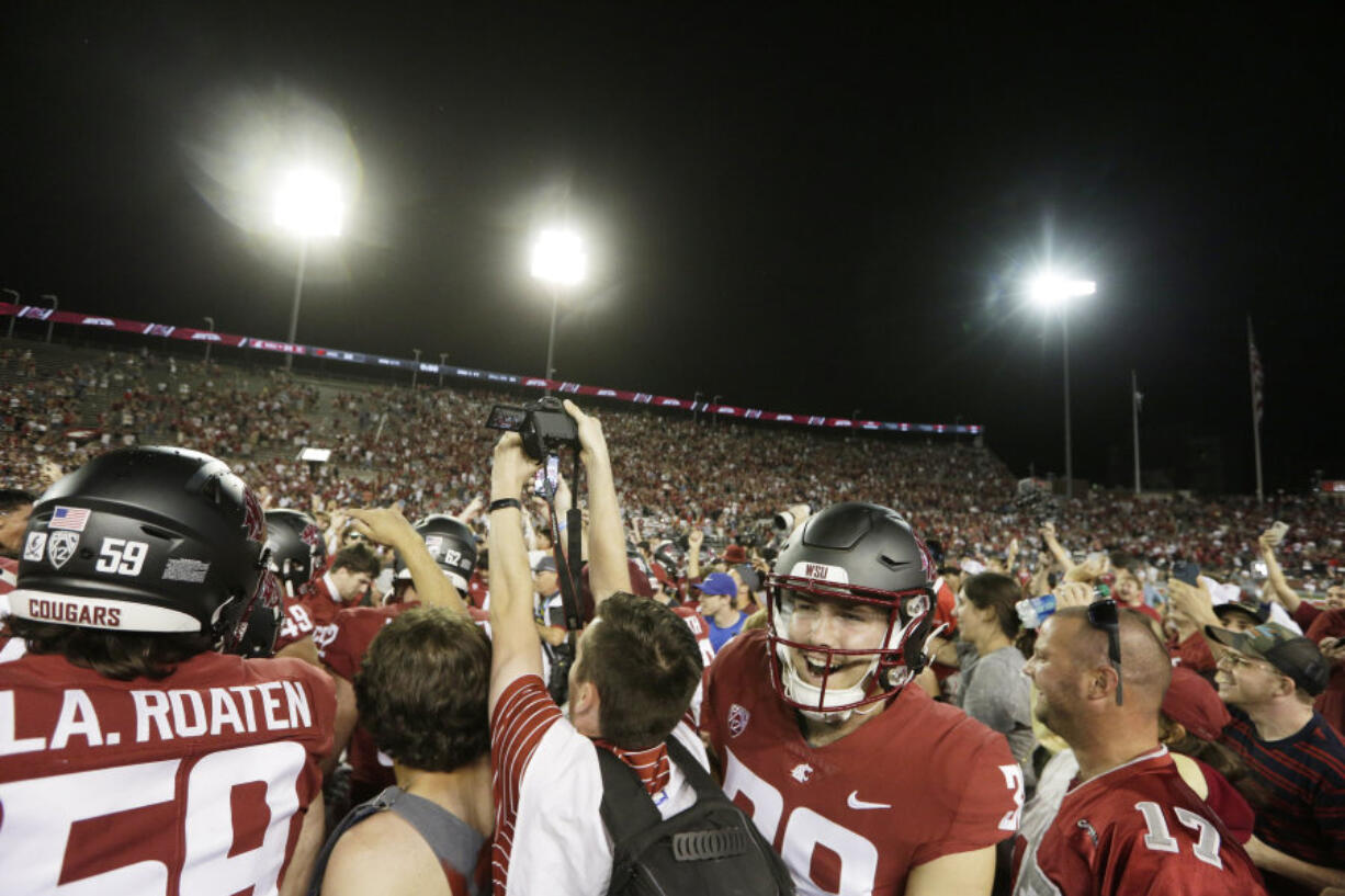 Washington State fans and players celebrate on the field after team's win over Wisconsin in an NCAA college football game, Saturday, Sept. 9, 2023, in Pullman, Wash.