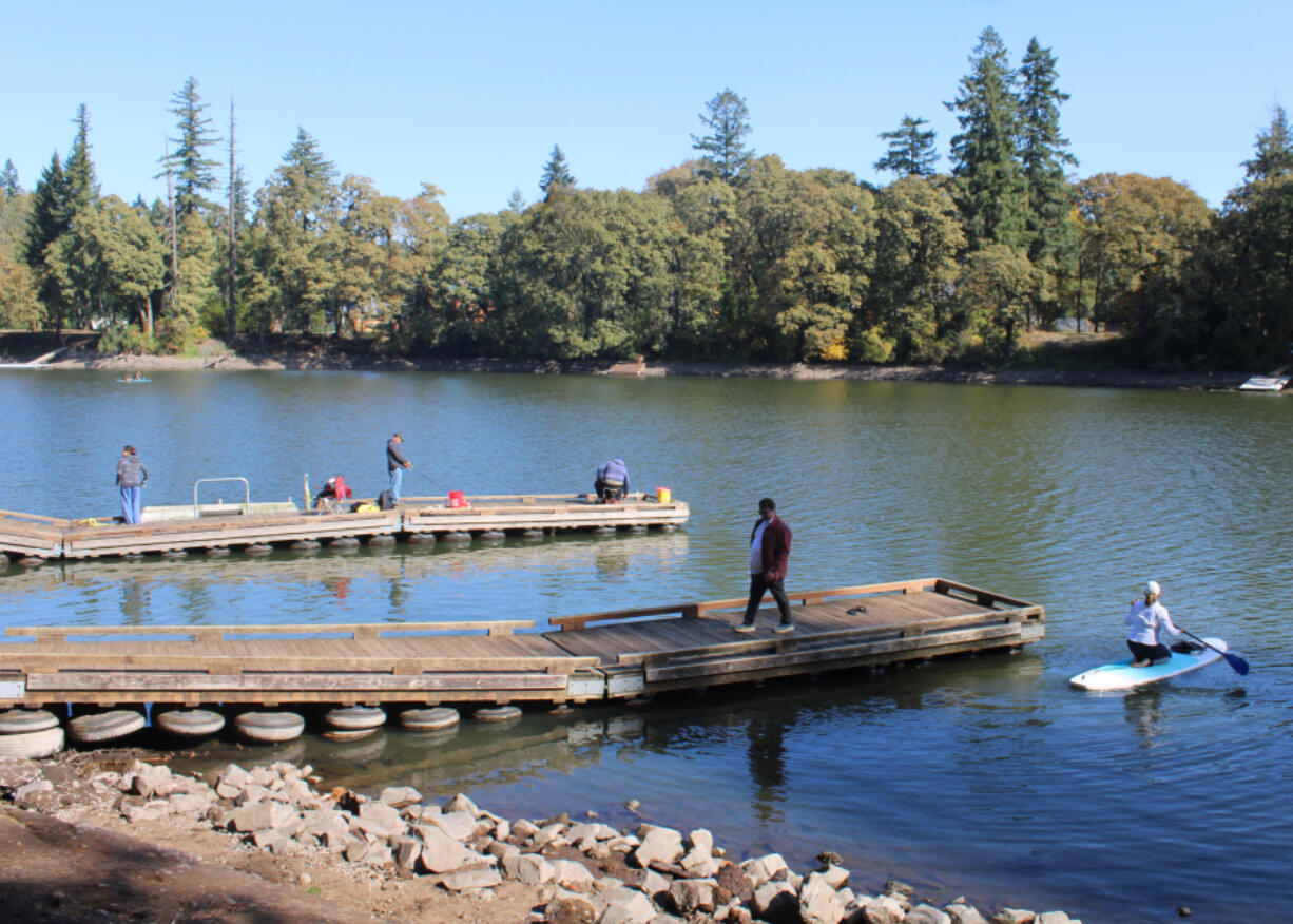 People gather on boat docks at Heritage Park in Camas as a kayaker paddles into Lacamas Lake on Sept. 30 following the annual Lacamas Lake cleanup event.