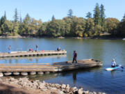 People gather on boat docks at Heritage Park in Camas as a kayaker paddles into Lacamas Lake on Sept. 30 following the annual Lacamas Lake cleanup event.