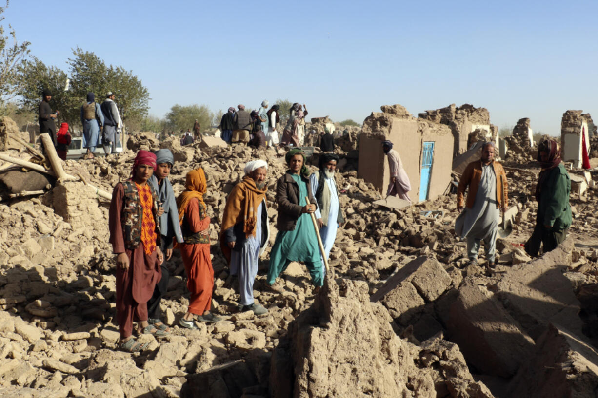 Afghans stand in a courtyard of their destroyed homes after an earthquake in Zenda Jan district in Herat province, of western Afghanistan, Sunday, Oct. 8, 2023. Powerful earthquakes killed at least 2,000 people in western Afghanistan, a Taliban government spokesman said Sunday. It's one of the deadliest earthquakes to strike the country in two decades.