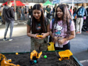 Students Camilla Arelano, left, and Leslie Robles play with toy diggers while exploring career options at the Dozer Day Career Fair.
