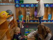 Walter Vizcaino, 2 1/2, plays with instructor Evelyn Polyakov, foreground, as other students put their things into their cubbies at WSU Vancouver's on-campus child care facility Oct. 4, 2023.