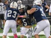 Skyview junior Rex Allinger, center, runs between teammates with pads Friday, Oct. 20, 2023, before Skyview’s win against Battle Ground at Kiggins Bowl.