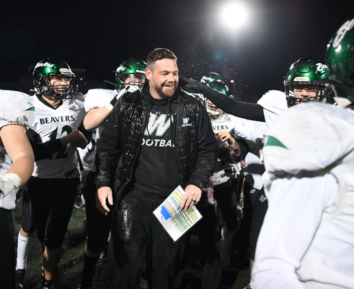 Players celebrate with Woodland head coach Sean McDonald after he was doused with water Friday, Oct, 27, 2023, after the Beavers’ 28-21 win against Ridgefield at Ridgefield High School. With the win, Woodland captured its first 2A Greater St. Helens League title since 2007.