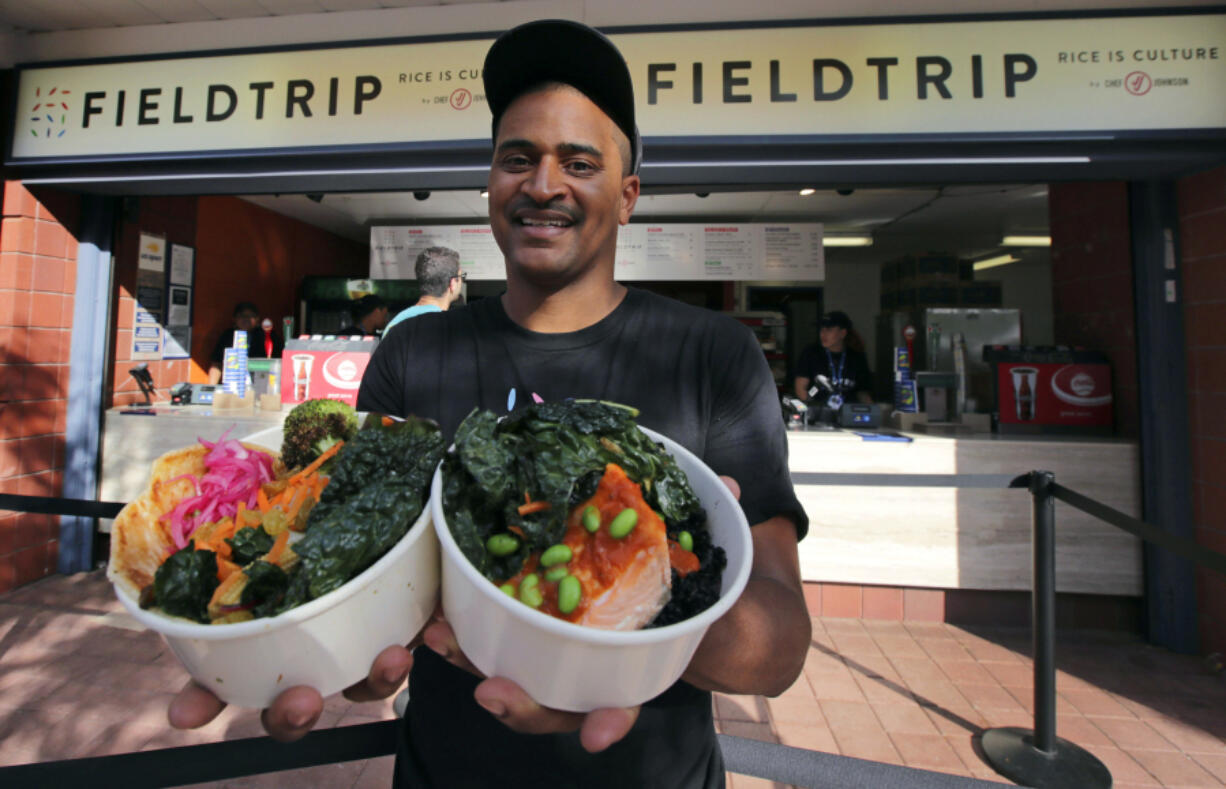 Chef JJ Johnson poses with his two signature rice bowls, one salmon and one vegetable, outside his Field Trip counter-service restaurant kiosk on the food court at the US Open tennis championships in New York.