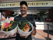 Chef JJ Johnson poses with his two signature rice bowls, one salmon and one vegetable, outside his Field Trip counter-service restaurant kiosk on the food court at the US Open tennis championships in New York.