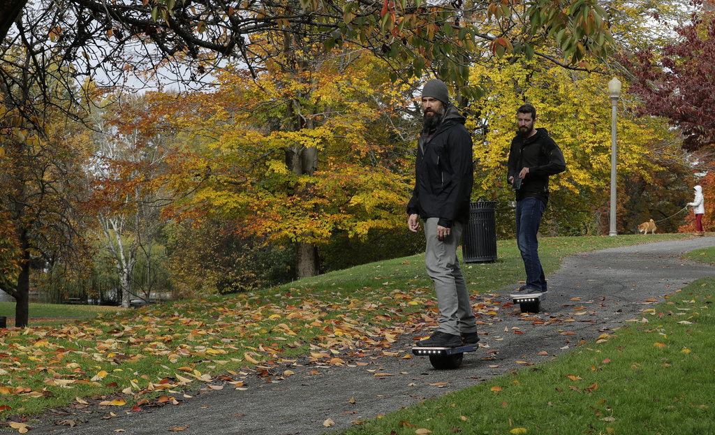 File - Two people ride Onewheels through Wright Park in Tacoma, Wash., on Oct. 26, 2018. All models of Onewheel self-balancing electric skateboards are under recall after at least four deaths and multiple injuries were reported in recent years, federal regulators said last week.(AP Photo/Ted S.