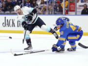 Seattle Kraken's Justin Schultz (4) passes the puck while under pressure from St. Louis Blues' Kasperi Kapanen (42) during the first period of an NHL hockey game Saturday, Oct. 14, 2023, in St. Louis.