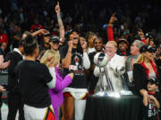 Las Vegas Aces' A'ja Wilson and Mark Davis celebrate with teammates next to the trophy after Game 4 of a WNBA basketball final playoff series against the New York Liberty Wednesday, Oct. 18, 2023, in New York. The Aces won 70-69.