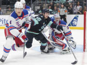 Seattle Kraken right wing Kailer Yamamoto (56) goes after the puck as New York Rangers defenseman Braden Schneider (4) and goaltender Jonathan Quick (32) defend during the second period of an NHL hockey game Saturday, Oct. 21, 2023, in Seattle.