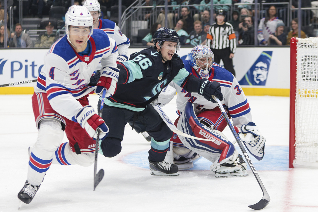 Seattle Kraken right wing Kailer Yamamoto (56) goes after the puck as New York Rangers defenseman Braden Schneider (4) and goaltender Jonathan Quick (32) defend during the second period of an NHL hockey game Saturday, Oct. 21, 2023, in Seattle.