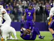 Washington quarterback Michael Penix Jr., bottom, curls up in a ball as running back Dillon Johnson (7) looks on after Arizona State defensive back Shamari Simmons recovered his fumble during the first half of an NCAA college football game Saturday, Oct. 21, 2023, in Seattle.