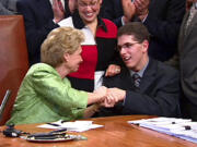 FILE - In this  May 14, 2009, file photo, made from video, then-Washington Gov. Chris Gregoire, left, shakes hands with Zackery Lystedt, right, in Olympia, Wash., after she signed the "Zackery Lystedt law", what is considered the nation's toughest law regulating when high school athletes can return to games after having sustained a concussion. It is named after Lystedt, who suffered a life-threatening brain injury in 2006 after he returned to play football following a concussion.