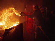 Francis Lopez douses flames with a bucket of water as a wildfire called the Highland Fire burns through his property in Aguanga, Calif., Monday, Oct. 30, 2023. A wildfire fueled by gusty Santa Ana winds ripped through rural land southeast of Los Angeles on Monday, forcing thousands of people from their homes, fire authorities said.