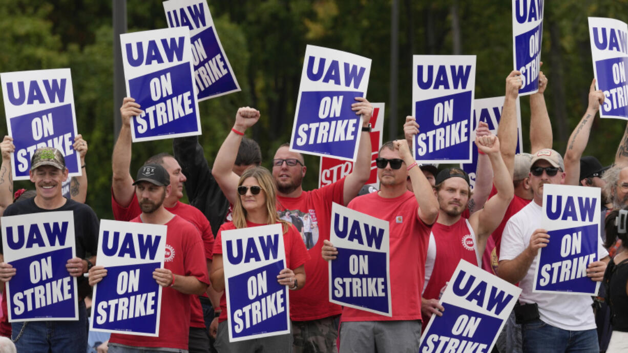 FILE - United Auto Workers members hold picket signs near a General Motors Assembly Plant in Delta Township, Mich., Sept. 29, 2023. As the auto workers strike approaches the one-month mark, more Americans sympathize with the striking workers than with the three big car companies that employ them. That's one of the findings in a new poll from The Associated Press-NORC Center for Public Affairs Research.