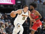 Denver Nuggets center Nikola Jokic, left, drives to the rim as Chicago Bulls guard Coby white defends in the first half of a preseason NBA basketball game Sunday, Oct. 15, 2023, in Denver.