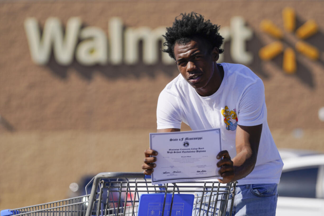 Bryant West, who has a job at a Walmart, holds a copy of his GED, as he poses for a portrait in Pascagoula, Miss., Friday, Oct. 20, 2023. Girls consistently are outperforming boys, graduating at higher rates at public high schools around the country.