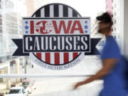 FILE - A pedestrian walks past a sign for the Iowa Caucuses on a downtown skywalk, in Des Moines, Iowa, on Feb. 4, 2020. Iowa's Democratic Party says it will hold a caucus on Jan. 15 but won't release the results until early March. It's an attempt to retain their state's leadoff spot on the presidential nominating calendar without violating a new national party lineup endorsed by President Joe Biden that has South Carolina going first for 2024.