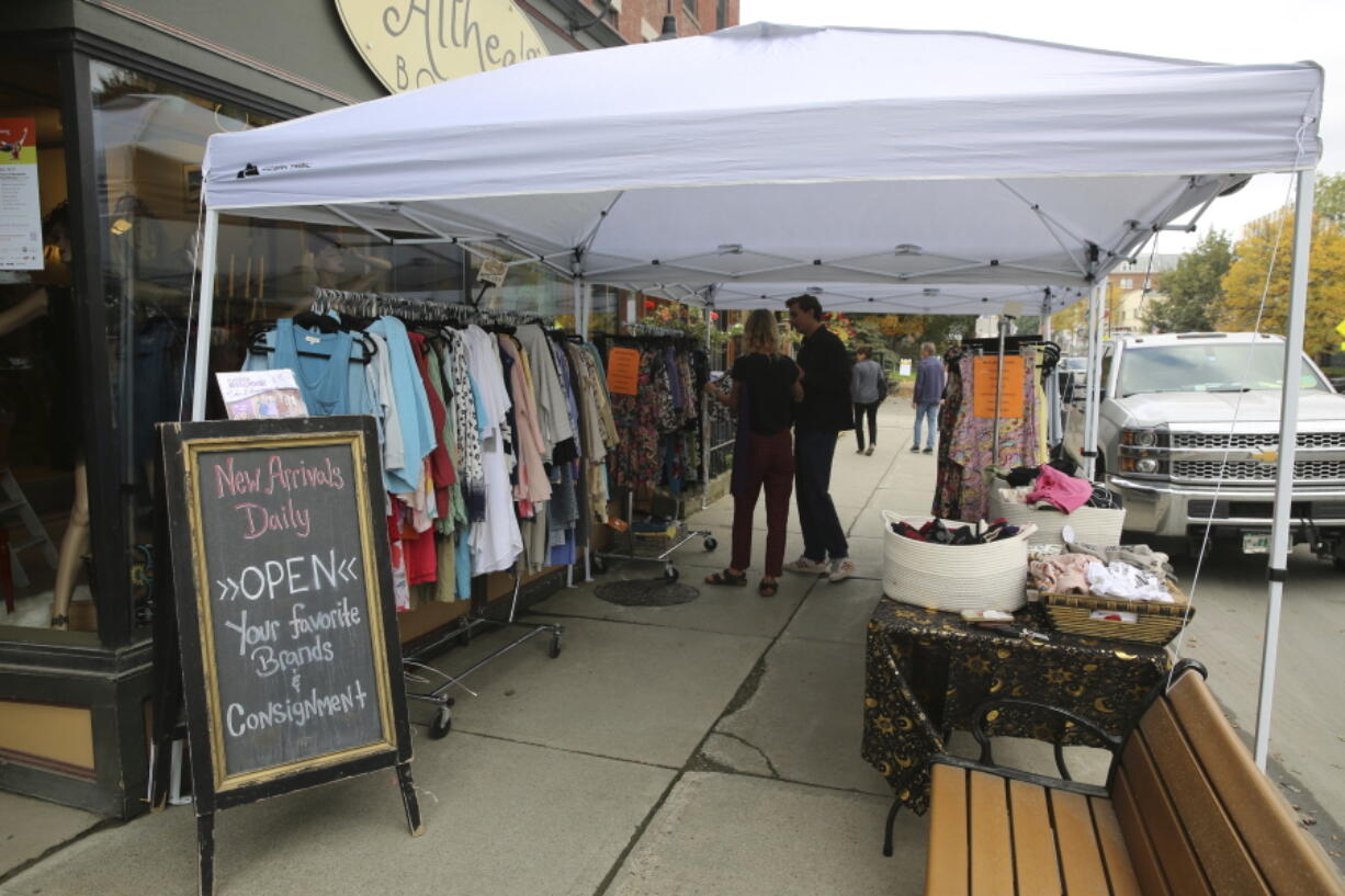 Shoppers stop at a sidewalk sale at Althea's Attic Boutique in Montpelier, Vt., on Friday, Oct. 6, 2023. Three months after flooding inundated the small city, Montpelier is holding a reopening celebration on Friday and Saturday to show the progress.