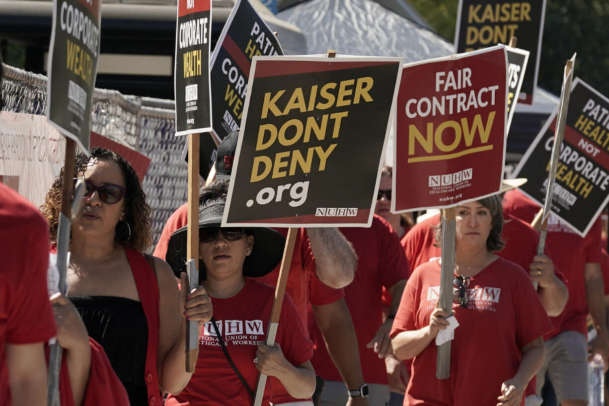 FILE - Kaiser Permanente mental health workers and supporters march outside a Kaiser facility in Sacramento, Calif., Aug. 15, 2022. Roughly 75,000 health care workers at the Kaiser Permanente hospital system are poised to go on a three-day strike at hospitals in California, Colorado, Oregon, Washington, Virginia and Washington, D.C.