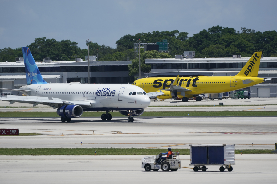 FILE - A JetBlue Airways Airbus A320, left, passes a Spirit Airlines Airbus A320 as it taxis on the runway, July 7, 2022, at the Fort Lauderdale-Hollywood International Airport in Fort Lauderdale, Fla.  The Biden administration's fight against consolidation in the airline industry will be tested Tuesday, Oct. 31, 2023 with lawyers for JetBlue Airways and the Justice Department due in court.