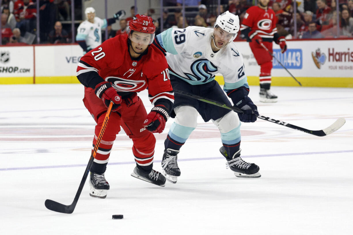 Carolina Hurricanes' Sebastian Aho (20) gathers in the puck on a breakaway as Seattle Kraken's Vince Dunn (29) gives chase during the second period of an NHL hockey game in Raleigh, N.C., Thursday, Oct. 26, 2023.