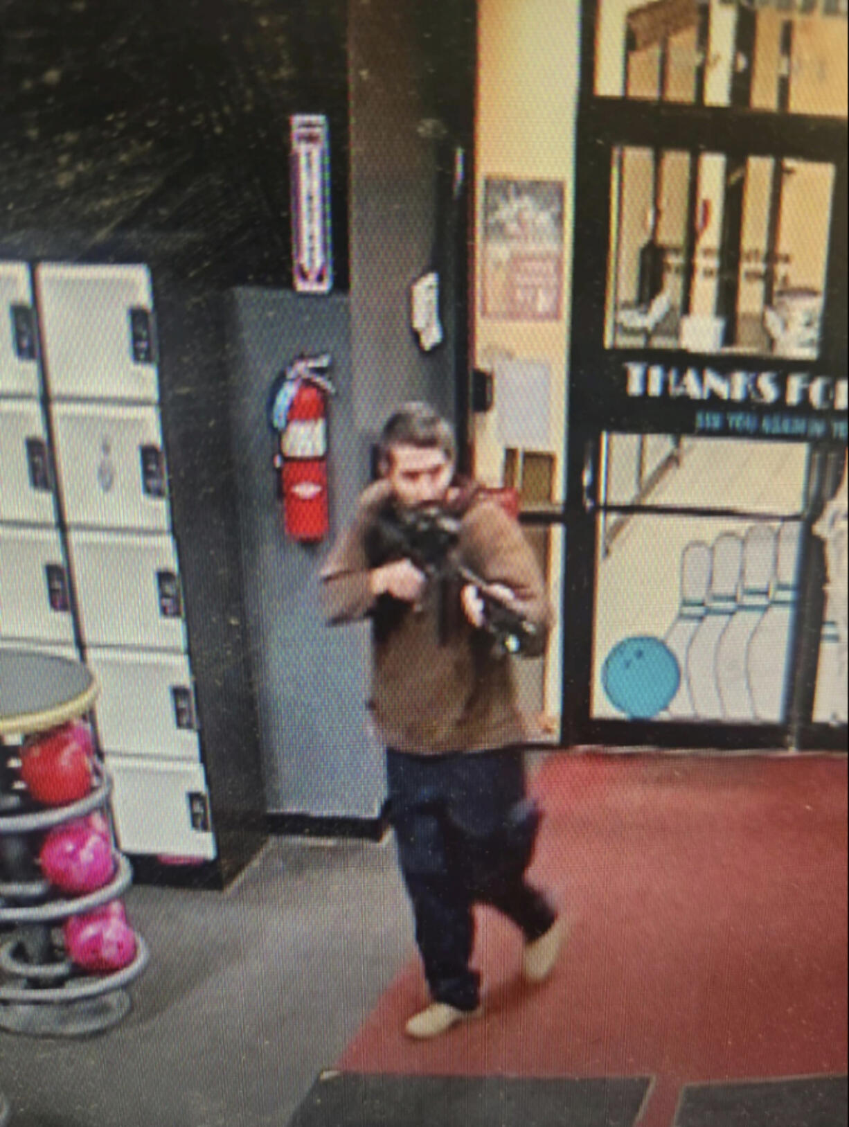 In this image taken from video released by the Androscoggin County Sheriff's Office, an unidentified shooter points a gun while entering Sparetime Recreation in Lewiston, Maine, on Wednesday, Oct. 25, 2023. Maine State Police ordered residents in the state's second-largest city to shelter in place Wednesday night as the suspect remains at large.