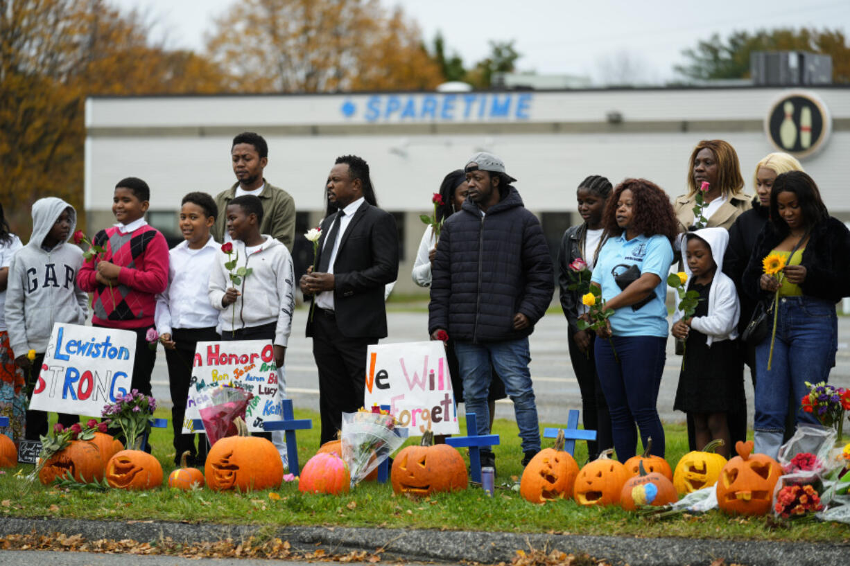 Members of the New Apostolic Church sing and pray at a makeshift memorial outside a bowling alley, the site of one of this week's mass shootings, Sunday, Oct. 29, 2023, in Lewiston, Maine. A gunman killed multiple people at the bowling alley and a bar in Lewiston on Wednesday.