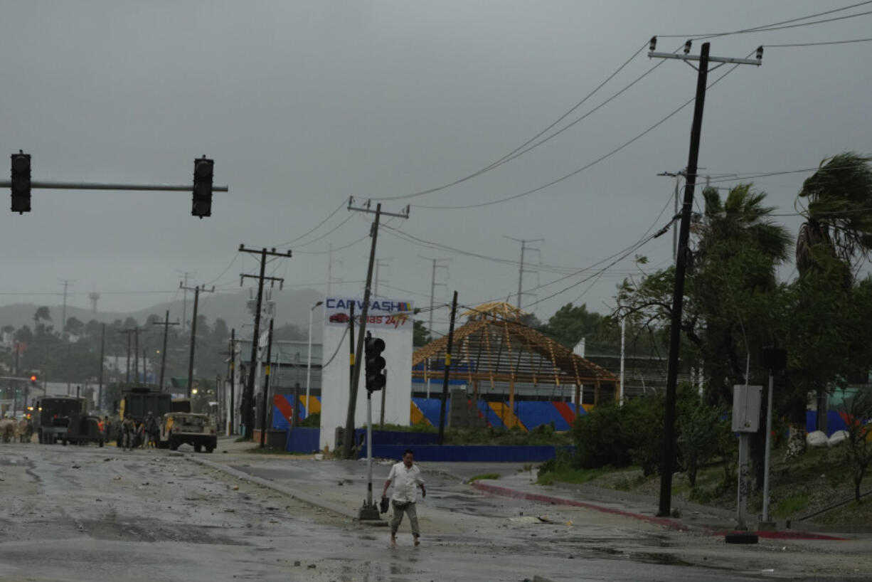 A man with his shoes off walks near an avenue flooded by the rains of Hurricane Norma in San Jose del Cabo, Mexico, Saturday, Oct. 21, 2023. Norma had weakened and was downgraded to Category 1 on the hurricane wind scale. It was located 25 miles west of Cabo San Lucas storm with winds of 85 mph (140 kmh) and expected to make landfall on Saturday, according to the U.S.