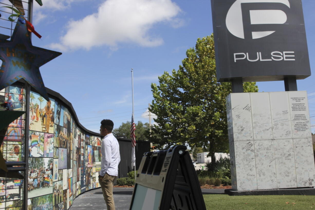 FILE - Brandon Wolf, a survivor of the Pulse nightclub shooting and activist, looks at the photos that are a part of the Pulse memorial in Orlando, Fla., on Sept. 9, 2022. The city of Orlando plans to purchase the gay nightclub property where 49 people were massacred seven years ago, in what at the time was the deadliest mass shooting in modern U.S. history, with the intention of building a memorial for the victims, Mayor Buddy Dyer said Wednesday, Oct. 18, 2023.