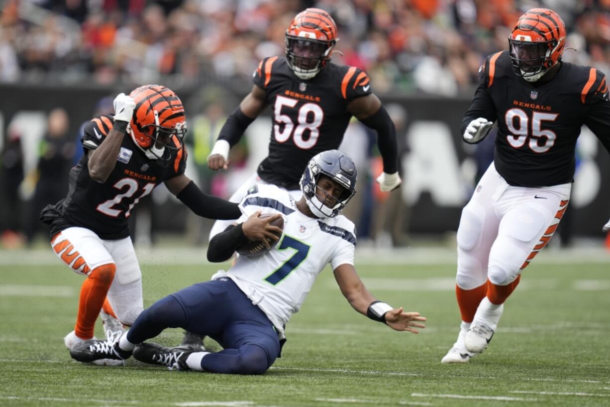 Seattle Seahawks quarterback Geno Smith slides in front of Cincinnati Bengals' Mike Hilton (21) during the second half of an NFL football game, Sunday, Oct. 15, 2023, in Cincinnati.