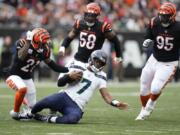 Seattle Seahawks quarterback Geno Smith slides in front of Cincinnati Bengals' Mike Hilton (21) during the second half of an NFL football game, Sunday, Oct. 15, 2023, in Cincinnati.