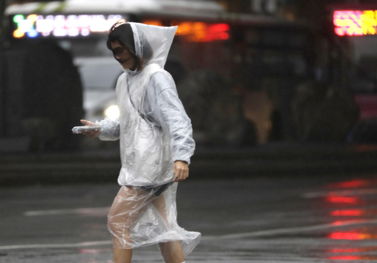 A woman walks in the rain as Typhoon Koinu approaches to Taiwan in Taipei, Taiwan, Wednesday, Oct. 4, 2023.