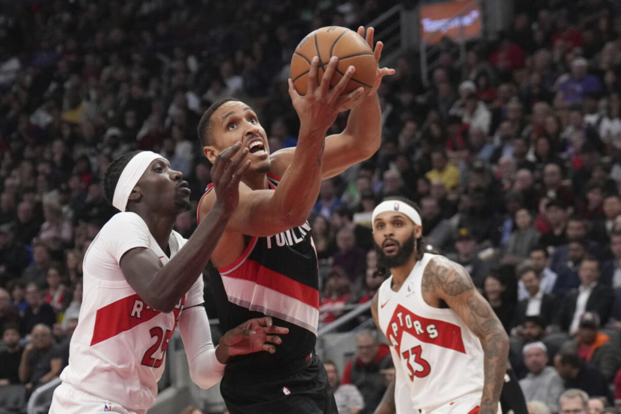 Portland Trail Blazers guard Malcolm Brogdon, center, drives to the net as Toronto Raptors forward Chris Boucher (25) defends during second-half NBA basketball game action in Toronto, Monday, Oct. 30, 2023.