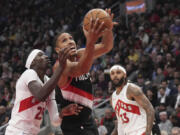 Portland Trail Blazers guard Malcolm Brogdon, center, drives to the net as Toronto Raptors forward Chris Boucher (25) defends during second-half NBA basketball game action in Toronto, Monday, Oct. 30, 2023.