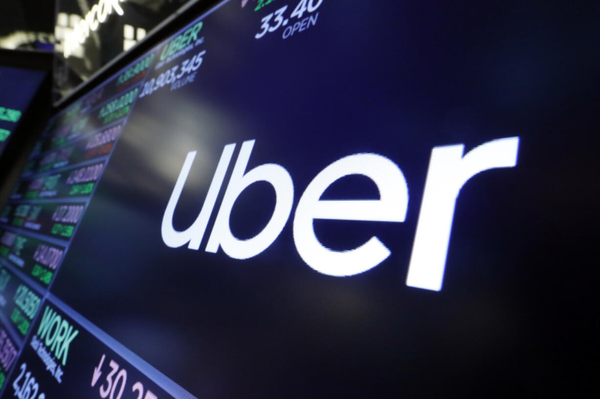 FILE - The logo for Uber appears above a trading post on the floor of the New York Stock Exchange, Aug. 16, 2019. The ride-hailing and delivery company said Wednesday, Oct. 4, 2023, that its drivers will collect up to five prepaid and sealed packages and drop them off at a local post office or at UPS or FedEx stores. Uber will charge a flat fee of $5 for the service or $3 for its Uber One members.