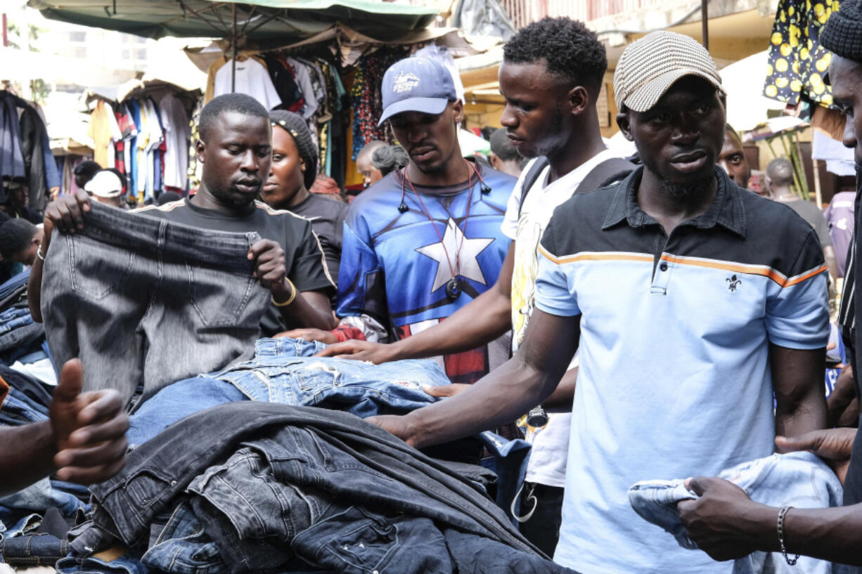 Ugandans buy second hand clothes at Owino Market, in Kampala, Uganda, Friday, Sept. 15, 2023. Jostling for space, human bodies mingle in the crowded footpaths crisscrossing this expansive open market in the Ugandan capital. The marketgoers are mostly looking for second-hand clothing, from underwear that feels new between hands to shoes that customers try on while being pushed to make way for others.