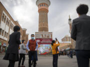 FILE - Tourists take photos near a tower at the International Grand Bazaar in Urumqi in western China's Xinjiang Uyghur Autonomous Region, as seen during a government organized trip for foreign journalists on April 21, 2021. Some U.S. lawmakers are demanding that seafood processed in two Chinese provinces be banned from entering the U.S. market. It's the latest effort by lawmakers to restrict imports of Chinese goods on the grounds of rights abuse, a move that is certain to irk Beijing at a time of tensions over trade and other issues.