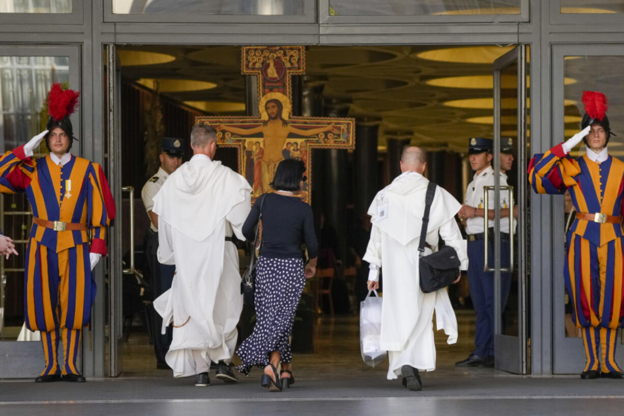 Delegates walk by the large Romanesque rood before which St. Francis of Assisi was praying when he is said to have received the commission from the Lord to rebuild the Church as they arrive for the opening session of the 16th General Assembly of the Synod of Bishops at The Vatican, Wednesday, Oct. 4, 2023. Pope Francis is convening a global gathering of bishops and laypeople to discuss the future of the Catholic Church, including some hot-button issues that have previously been considered off the table for discussion. Key agenda items include women's role in the church, welcoming LGBTQ+ Catholics, and how bishops exercise authority. For the first time, women and laypeople can vote on specific proposals alongside bishops.