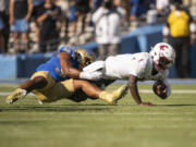 UCLA linebacker Darius Muasau (53) tackles Washington State quarterback Cameron Ward (1) for a sack during an NCAA football game on Saturday, Oct. 7, 2023, in Los Angeles.