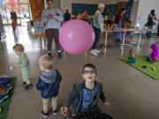 Parker Harris, 4, of Vancouver, center, watches in awe as a balloon takes flight while playing with a wind tunnel at the Fourth Plain Community Commons. The interactive play space is a partnership between Columbia Play Project and Fourth Plain Forward.