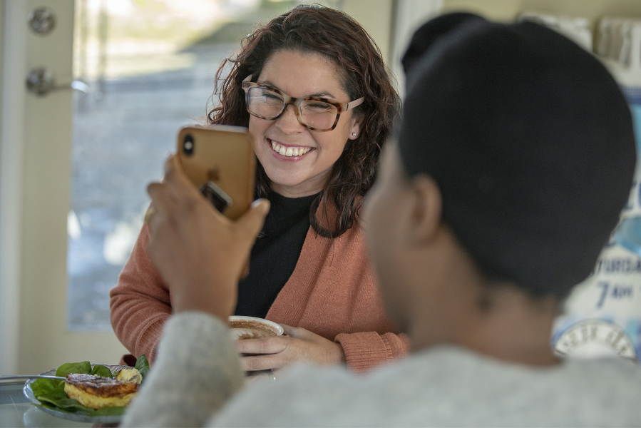 Rep. Monica Stonier, left, chats with Sybill Hyppolite, government affairs director for the Washington State Labor Council, as they share family photos at Latte Da Coffee House &amp; Wine Bar on Monday afternoon.