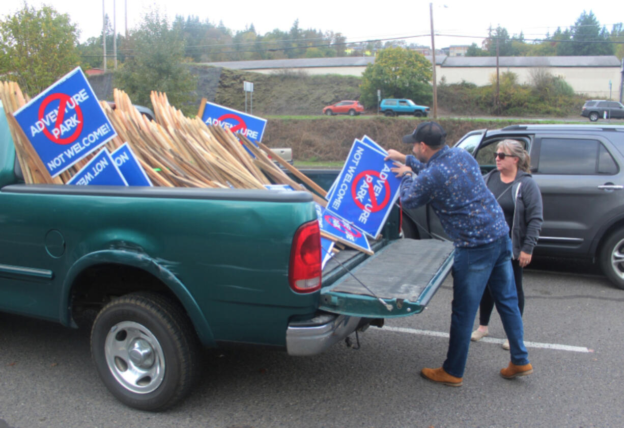 Camas resident Roman Battan, left, gives "Adventure park not welcome!" yard signs to a rural Washougal resident Oct. 23 at the Riverside Bowl Skatepark in Camas.