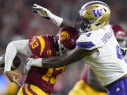 Washington defensive end Zion Tupuola-Fetui, right, forces a fumble by Southern California quarterback Caleb Williams during the first half of an NCAA college football game Saturday, Nov. 4, 2023, in Los Angeles.