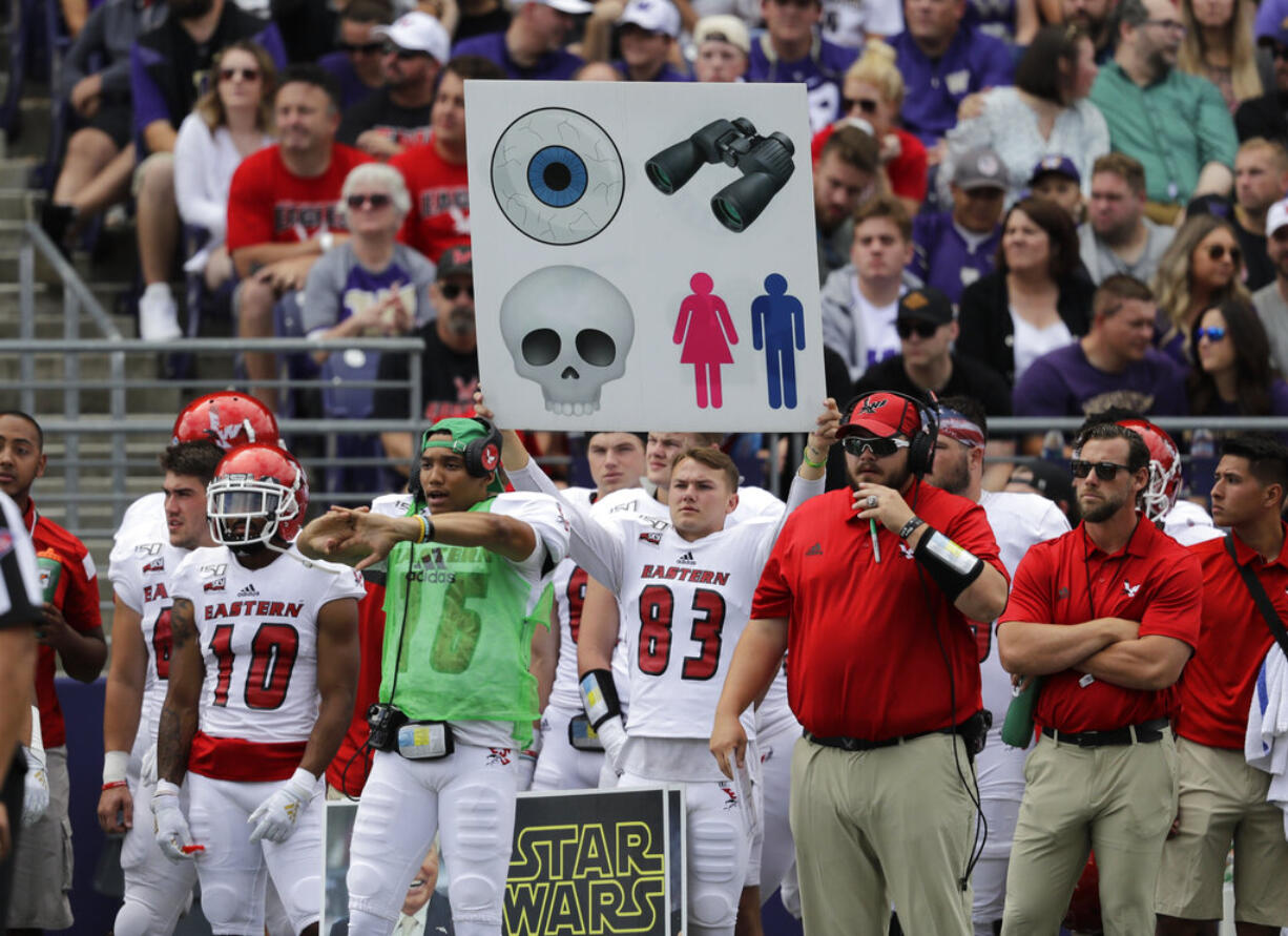 Sign held up from the sideline are used to send in plays. Or could also just be a decoy. Either way, it's becoming rather archaic system still used in college football.