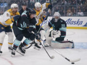 Seattle Kraken defenseman Brian Dumoulin (8) tries to keep the puck away from Nashville Predators left wing Filip Forsberg (9) and right wing Luke Evangelista (77) as Kraken goaltender Philipp Grubauer (31) watches during the first period of an NHL hockey game Thursday, Nov. 2, 2023, in Seattle.