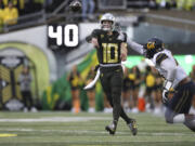 Oregon quarterback Bo Nix (10) throws a pass as California linebacker Xavier Carlton, right, defends during the first half of an NCAA football game, Saturday, Nov. 4, 2023, in Eugene, Ore.