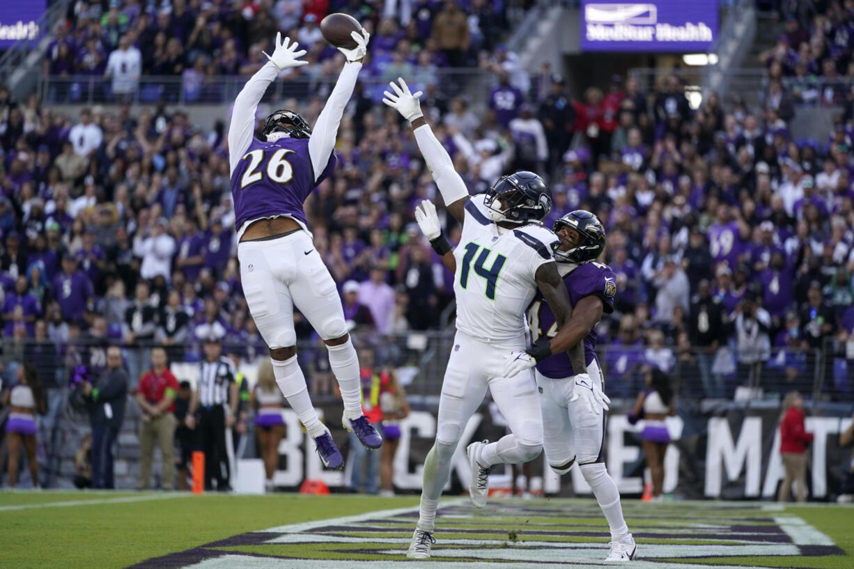 Baltimore Ravens safety Geno Stone (26) and cornerback Marlon Humphrey, right, break up a pass intended for Seattle Seahawks wide receiver DK Metcalf (14) during the second half of an NFL football game, Sunday, Nov. 5, 2023, in Baltimore.